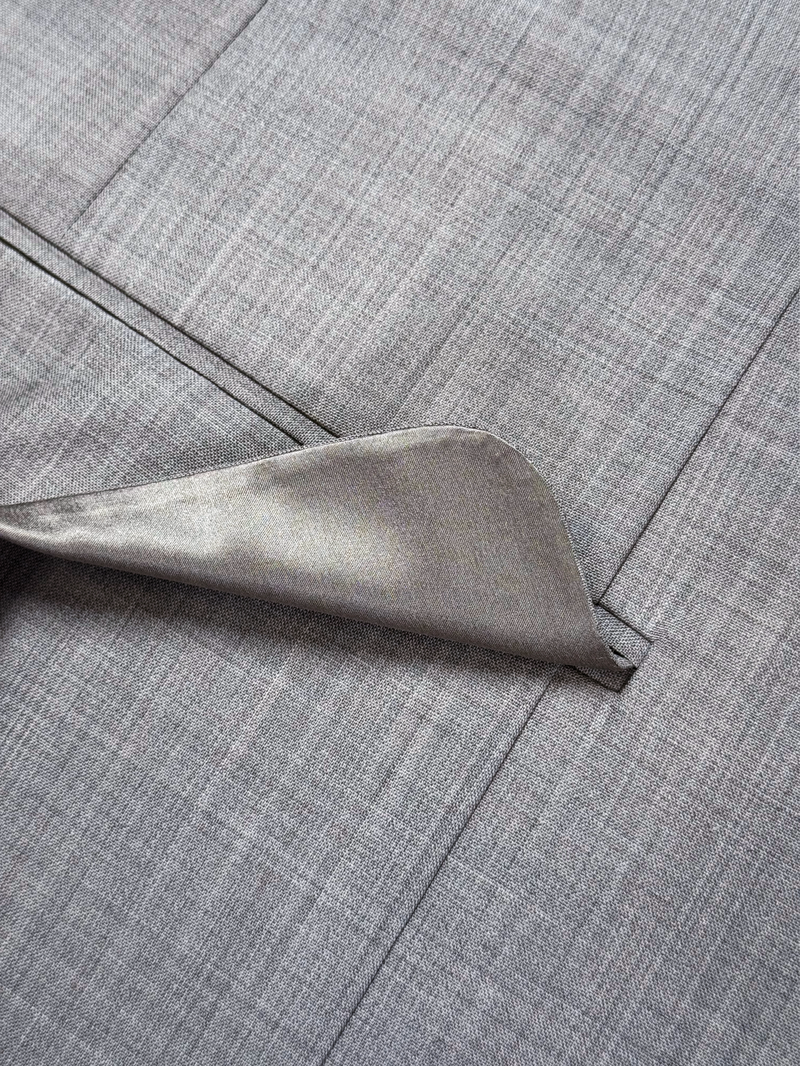 Close-up of the flap pocket and hand-stitched details on a taupe gray melange wool suit jacket